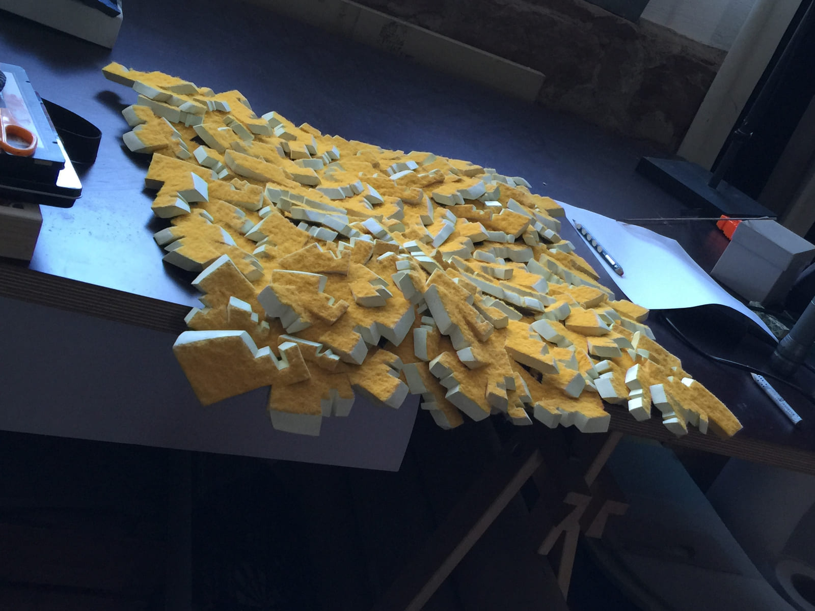 Gelbe Reliefteile während der Zusammenstellung auf einem Arbeitstisch.
