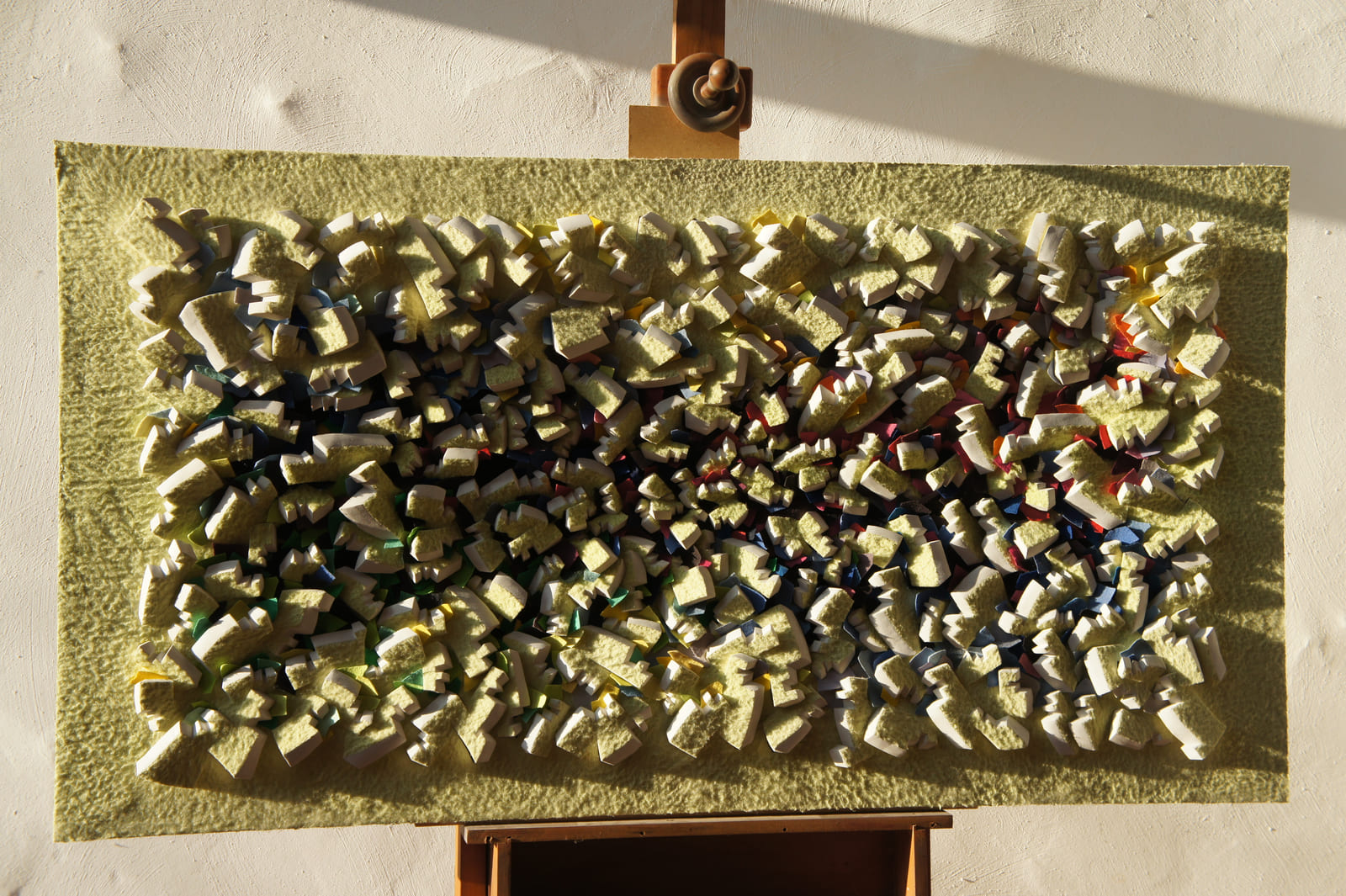 Gelbes Relief mit farbigen Zwischenlagen und ausgeprägten Schatten.