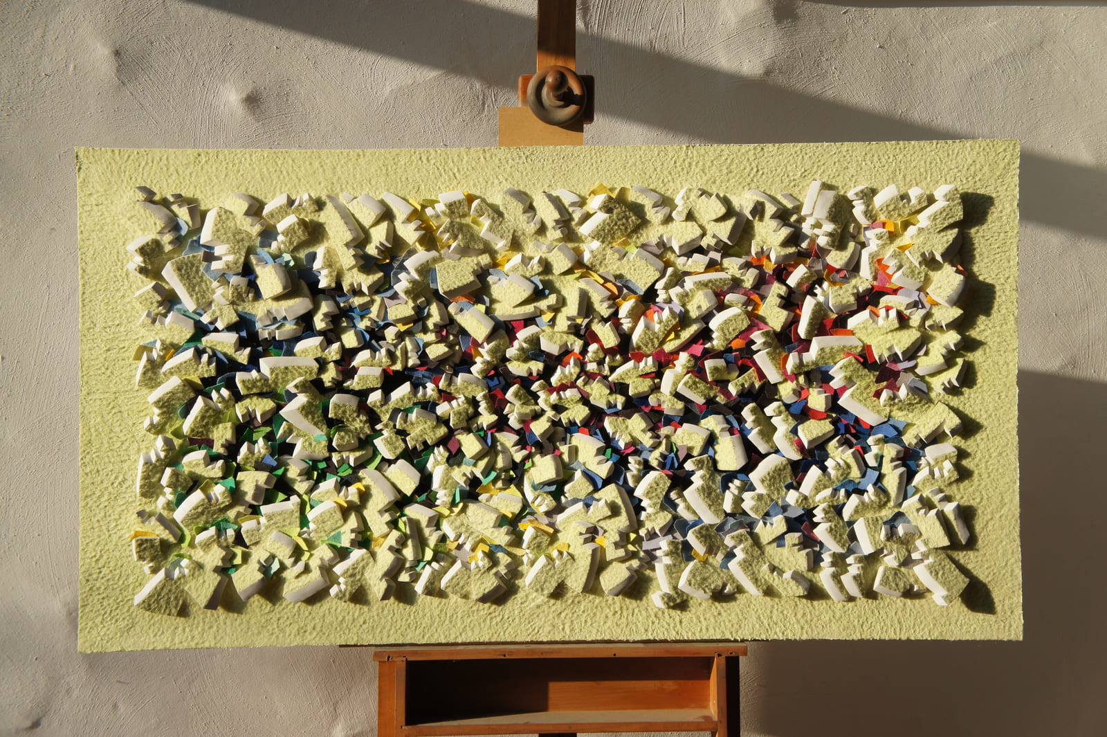 Dichtes gelbes Relief auf einer Staffelei, beleuchtet von seitlichem Sonnenlicht.