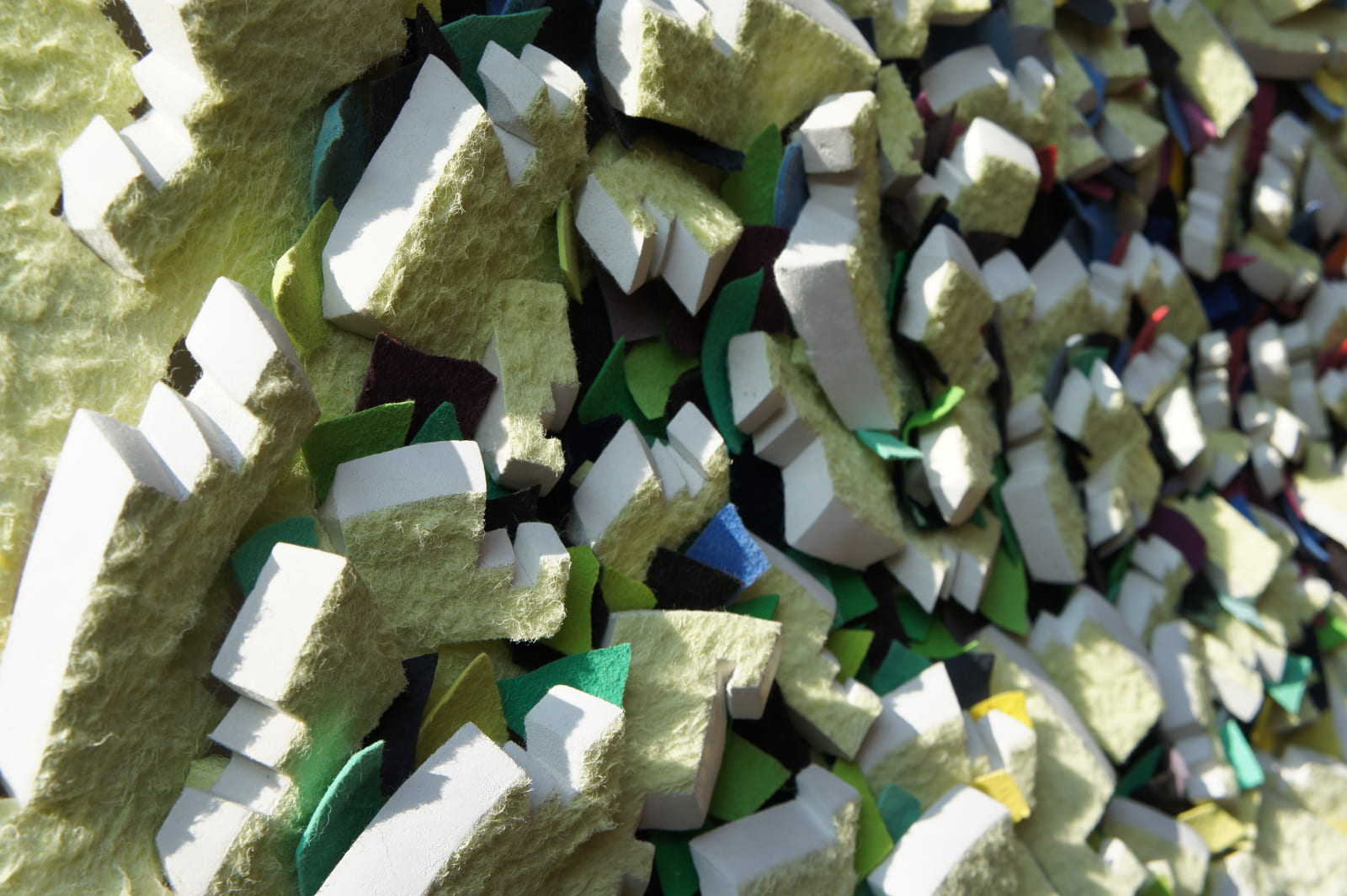 Seitlicher Nahblick auf gelbe Faserflächen, weiße Schnittkanten und grüne Zwischenlagen im Sonnenlicht.