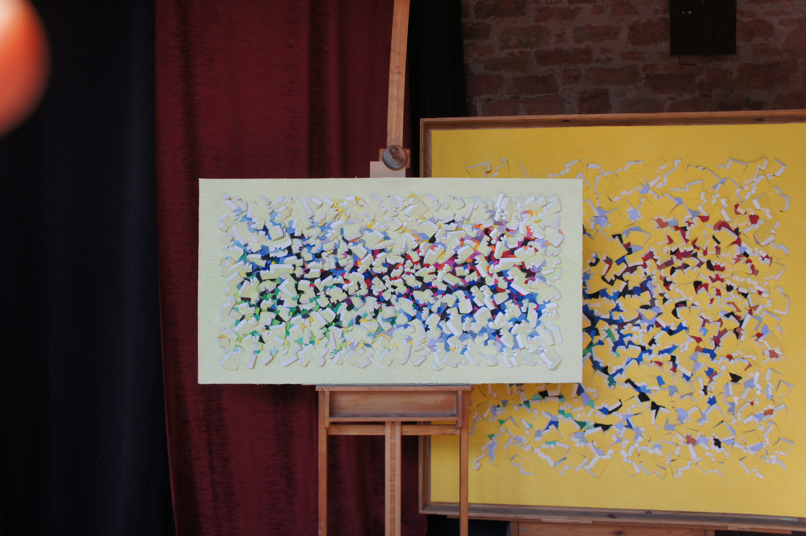 Gelbes Relief mit farbigen Zwischenlagen vor einer weiteren Arbeit im Atelier.