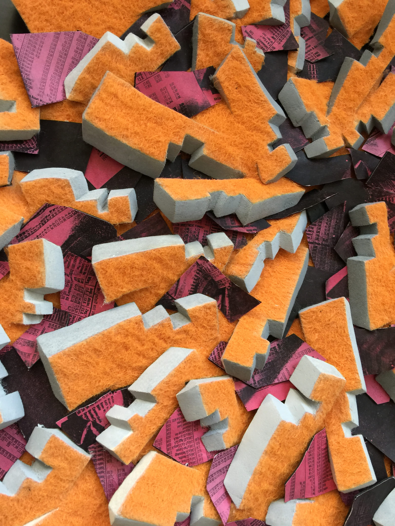 Orangefarbene Reliefteile mit hellen Schnittkanten über rosa und schwarzen bedruckten Zwischenlagen.